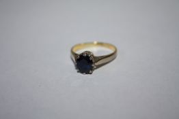 A HALLMARKED 18 CARAT GOLD DRESS RING, set with a single dark blue sapphire type stone, approx