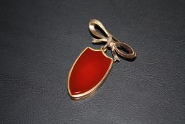 A HALLMARKED 9 CARAT GOLD BOW BROOCH, with suspended shield shaped locket engraved on one side and
