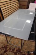 A MODERN GLASS TOPPED DINING TABLE ON TWO METAL STANDS 180 X 85 CM