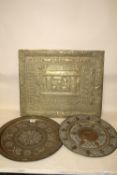 TWO EASTERN STYLE BRASS CHARGERS TOGETHER WITH AN EASTERN EMBOSSED BRASS PANEL, 61 X 51 CM (3)