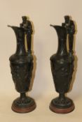 A PAIR OF BRONZE BACCHUS EWERS, seeing Bacchus squeezing a bunch of grapes into the ewer as he