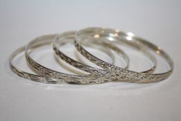 A SET OF FOUR VINTAGE SILVER ENGRAVED BANGLES - APPROX 32G