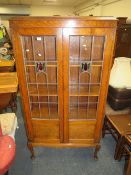 A 1920'S OAK LEADED AND GLAZED TALL BOOKCASE ON SLENDER CABRIOLE SUPPORTS H-175 W-93 CM