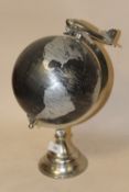 A MODERN CHROME EFFECT TABLE TOP GLOBE WITH AEROPLANE FINIAL
