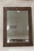 AN OAK FRAMED MIRROR WITH FLORAL CARVED DETAIL - OVERALL SIZE 81 CM BY 59 CM