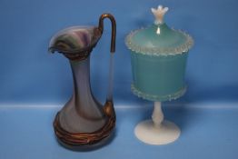 AN OPALESCENT LIDDED GOBLET TOGETHER WITH A COLOURED GLASS JUG (2)