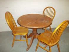 A SOLID PINE ROUND SINGLE PEDESTAL DINING TABLE SET WITH THREE CHAIRS