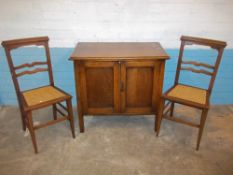 AN OAK TWO DOOR HALL CUPBOARD AND TWO EDWARDIAN CHAIRS