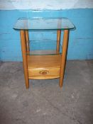 A BLONDE ERCOL GLASS TOPPED SIDE TABLE WITH DRAWER