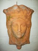 A TERRACOTTA WALL HANGING PLANTER DEPICTING A FACE