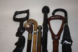 A COLLECTION OF MOSTLY MODERN WALKING STICKS TO INCLUDE A CARVED TRIBAL STYLE EXAMPLE TOGETHER