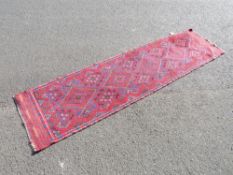 AN EASTERN WOOLLEN RUNNER RUG MAINLY RED GROUND 260 X 63 CM