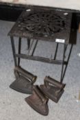 THREE VINTAGE CAST METAL IRONS ON A CAST METAL TRIVET STAND, TRIVET STAND HEIGHT - 33CM
