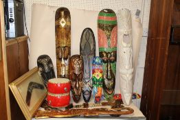 A COLLECTION OF TREEN TO INCLUDE TRIBAL STYLE MASKS, FRAMED AND GLAZED BOOMERANG, BONGO DRUMS ETC