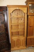 A HONEY PINE OPEN BOOKCASE WITH CUPBOARD H- W- CM