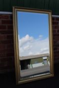 A LARGE CONTEMPORARY GILT FRAMED WALL MIRROR 75 X 128 CM