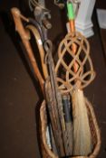 A WICKER BASKET CONTAINING CARPET BEATER, QUANTITY OF WALKING STICKS, A BROOM ETC.