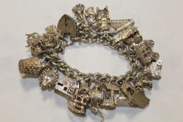 A HALLMARKED SILVER CHARM BRACELET WITH A LARGE QUANTITY OF CHARMS APPROX WEIGHT 136.5G