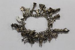 A SILVER CHARM BRACELET WITH A LARGE QUANTITY OF CHARMS APPROX WEIGHT 63.4G