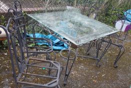 A HEAVY METAL GARDEN TABLE WITH GLASS TOP AND FOUR CHAIRS