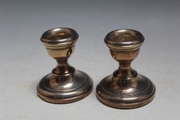 A SMALL PAIR OF HALLMARKED SILVER SQUAT CANDLESTICKS - BIRMINGHAM 1970, having filled bases, H 6 cm