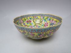 A CHINESE FINE PORCELAIN IMPERIAL YELLOW FAMILLE ROSE SCALLOPED BOWL, profusely decorated with