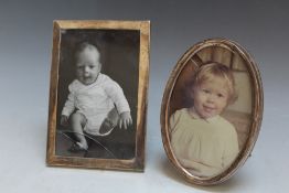 TWO HALLMARKED SILVER PHOTO FRAMES, consisting of an oval example by Sanders and Mackenzie -