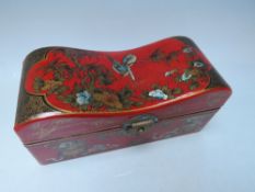 A DECORATIVE ORIENTAL RED LACQUERED STORAGE BOX, of rectangular form, with shaped hinged lid,