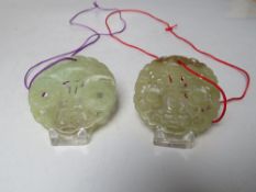 TWO CHINESE JADE CARVED AND PIERCED CIRCULAR PENDANTS, both with typical pierced carved