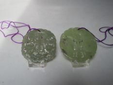 TWO CHINESE JADE CARVED AND PIERCED CIRCULAR PENDANTS, both with typical pierced carved