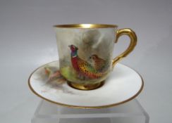 A ROYAL WORCESTER HAND PAINTED COFFEE CAN AND SAUCER, signed Jas Stinton, both items with game