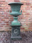 A VICTORIAN STYLE CAST METAL SHAPED GARDEN URN, raised on plinth, with twin handles and foliate