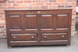 A GEORGIAN OAK OVERSIZED MULE CHEST, the hinged lid above a four panel front and twin drawers below,