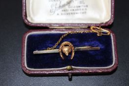 A 9CT GOLD FOX AND HORSESHOE BAR BROOCH, the back of the centre piece is stamped 15ct,, with