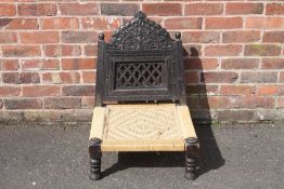 AN UNUSUAL EBONISED TRIBAL LOW STOOL / SEAT, the carved and pierced folding hinged back, above a