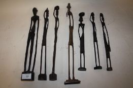 A SLENDER AFRICAN BRASS FIGURE TOGETHER WITH SIX SLENDER CARVED WOODEN AFRICAN FIGURES (7)