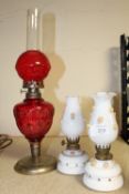 A PAIR OF SMALL OPAQUE GLASS OIL LAMPS WITH FLORAL DETAIL TOGETHER WITH A RED GLASS EXAMPLE (3)
