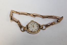 A 9 CARAT GOLD CASED ROTARY WRIST WATCH ON 9 CT EXPANDABLE STRAP