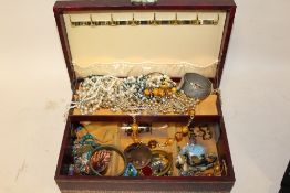 A RED LEATHER JEWELLERY BOX CONTAINING COSTUME JEWELLERY