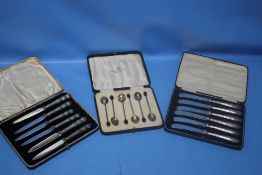 TWO CASED SETS OF SILVER HANDLED KNIVES together with a cased set of white metal coffee bean spoons