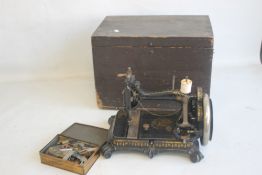 A VICTORIAN CAST SEWING MACHINE, black painted with gilt decoration, raised on four scroll feet in