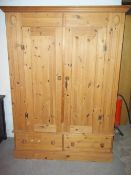 A TWO DOOR, TWO DRAWER SOLID PINE WARDROBE
