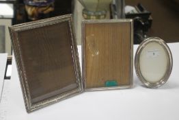 TWO HALLMARKED SILVER PICTURE FRAMES together with a white metal frame, the largest 23 x 17.5 cm