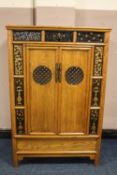 A CHINESE ELM TWO DOOR CABINET, the twin doors with circular pierced panels opening to reveal two m