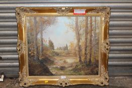A GILT FRAMED OIL ON CANVAS OF A MOUNTAINOUS WOODED LANDSCAPE - OVERALL SIZE - 66CM X 75CM