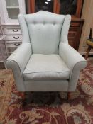 A CONTEMPORARY GREEN UPHOLSTERED WING ARMCHAIR