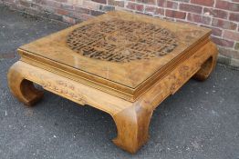 A LARGE CHINESE ELM PIERCED AND CARVED LOW TABLE, supported on four heavy scrolling feet, the top