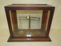 A SMALL GLASS CASED SET OF SCALES