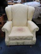 A MODERN UPHOLSTERED WING ARMCHAIR - A/F STAINED TO THE SEAT