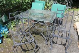 A GLASS TOPPED METAL FRAMED GARDEN TABLE WITH FOUR CHAIRS